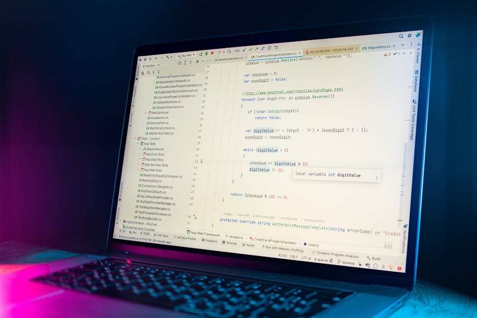 A close-up view of a modern laptop displaying lines of computer code on the screen. The screen shows a programming interface with syntax highlighting, including variables and functions related to soft